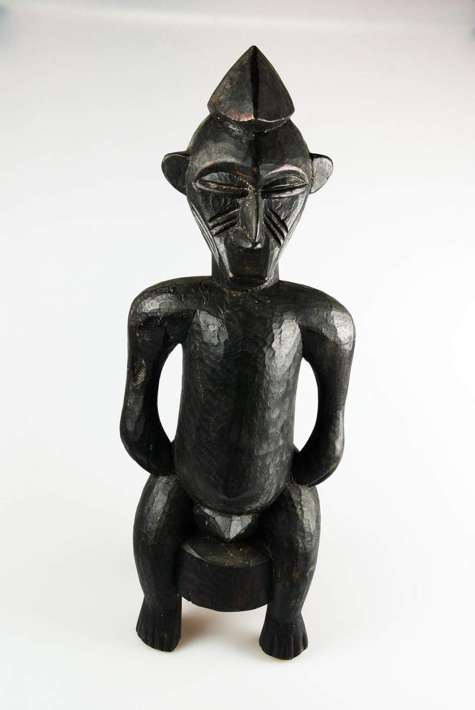 Männliche Figur auf Hocker sitzend