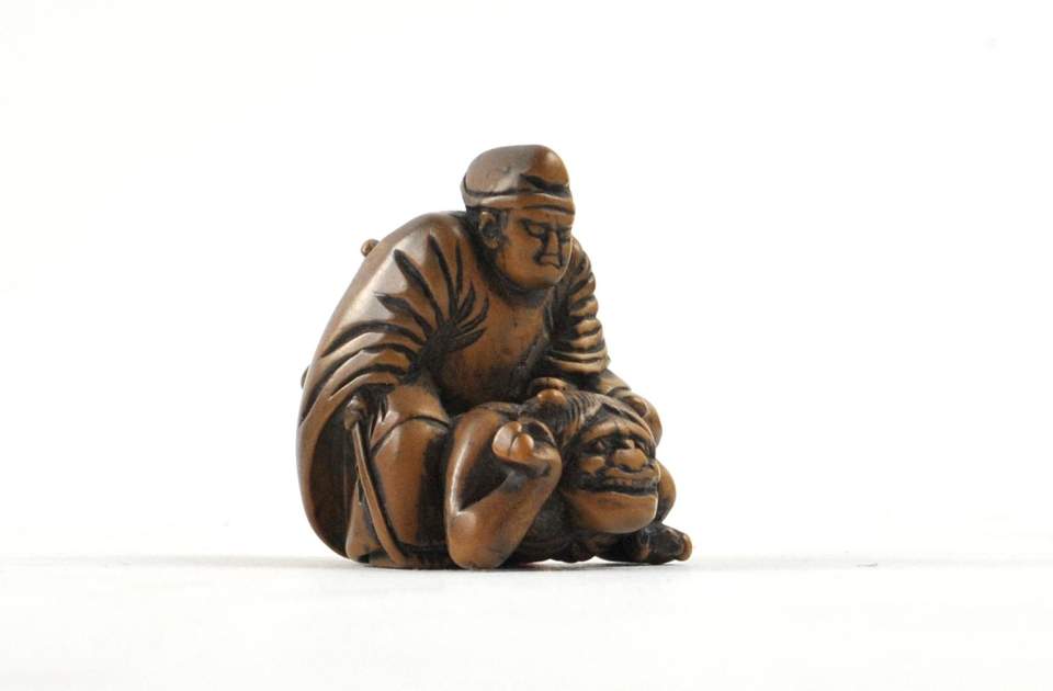 Netsuke Mann auf liegendem Teufel sitzend